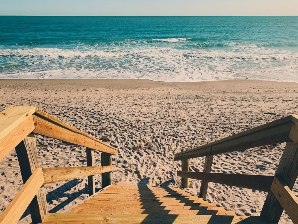 brown wooden stairs on sand seashore during day